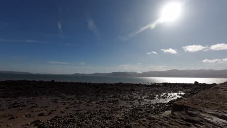 Bright-sunny-Wales-UK-mountain-pebble-coastline-idyllic-horizon-timelapse