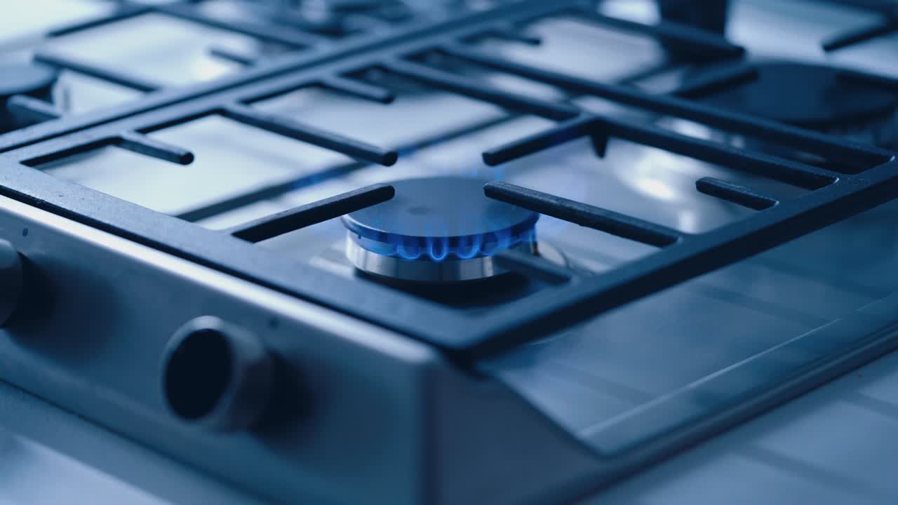 Gas Stove In The Kitchen. Burning blue flames of gas on cook top under grills in kitchen