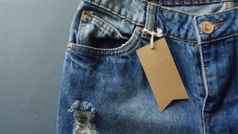 close up of jeans with tag on grey background with copy space