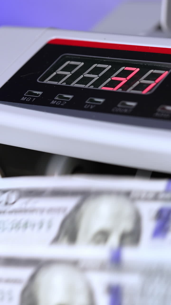 Electronic cash money counter. Counter machine is processing american money banknotes. Mechanism for bank financial operations. Finance concept. Close-up. Vertical video