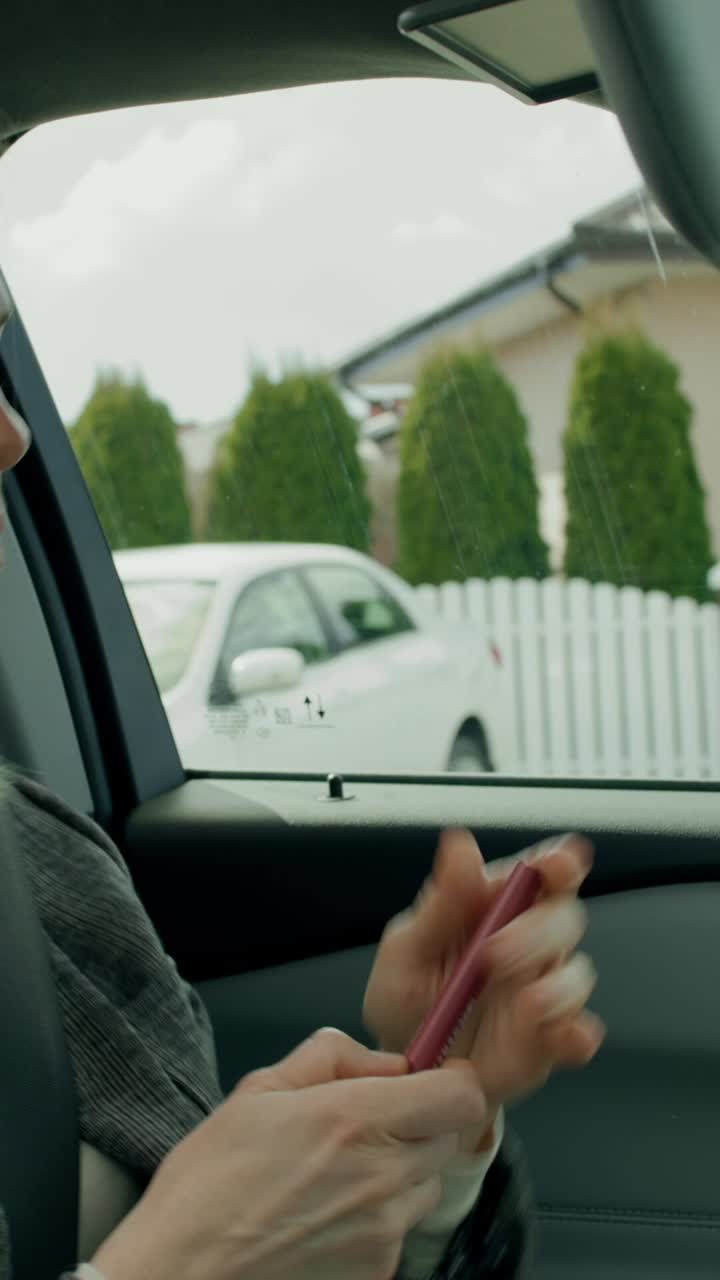 mujer aplicando lápiz labial en un coche