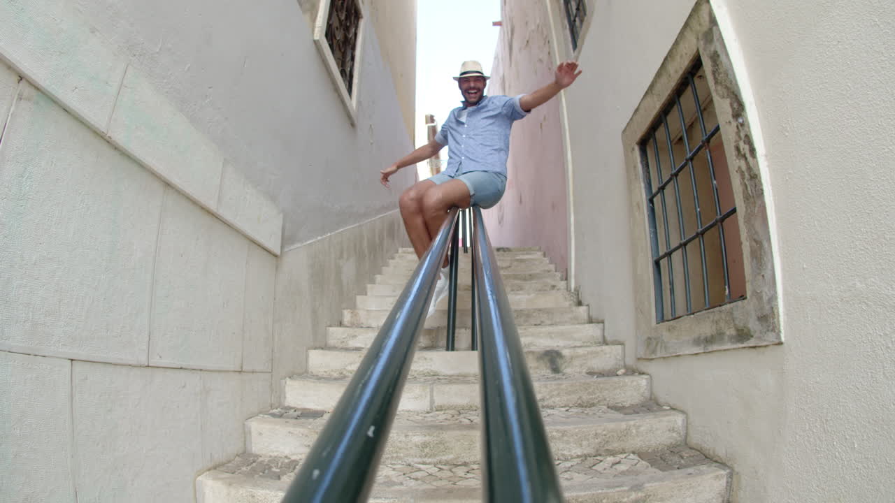 좁은 거리에서 계단 난간 아래로 미끄러지는 남자의 긴 샷