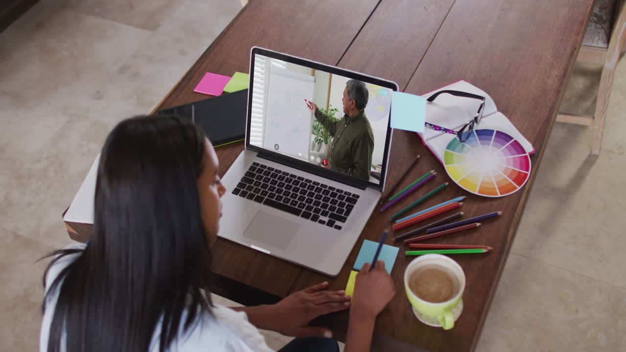 Alumna caucásica usando computadora en videollamada con un maestro, escribiendo