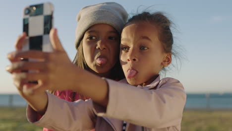 close up portrait of happy little girls posing making faces taking selfie photo using smartphone camera technology