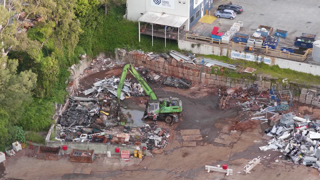 Drone captures a junkyard with machinery sorting metal under daylight in Gold Coast, Australia. Industrial and environmental focus