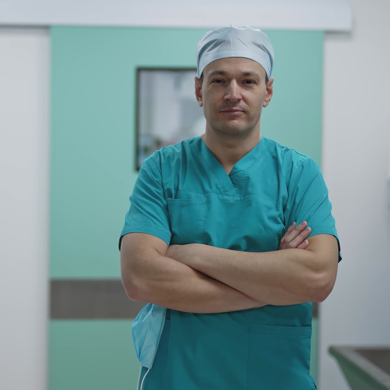 Portrait of the professional surgeon looking into camera after successful operation. In the background modern hospital operating room