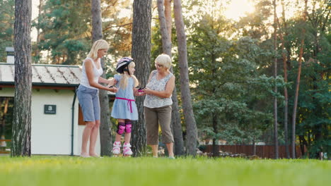 mom and grandmother are taught to roller-skate a girl of 6 years support her by the hand concept - t