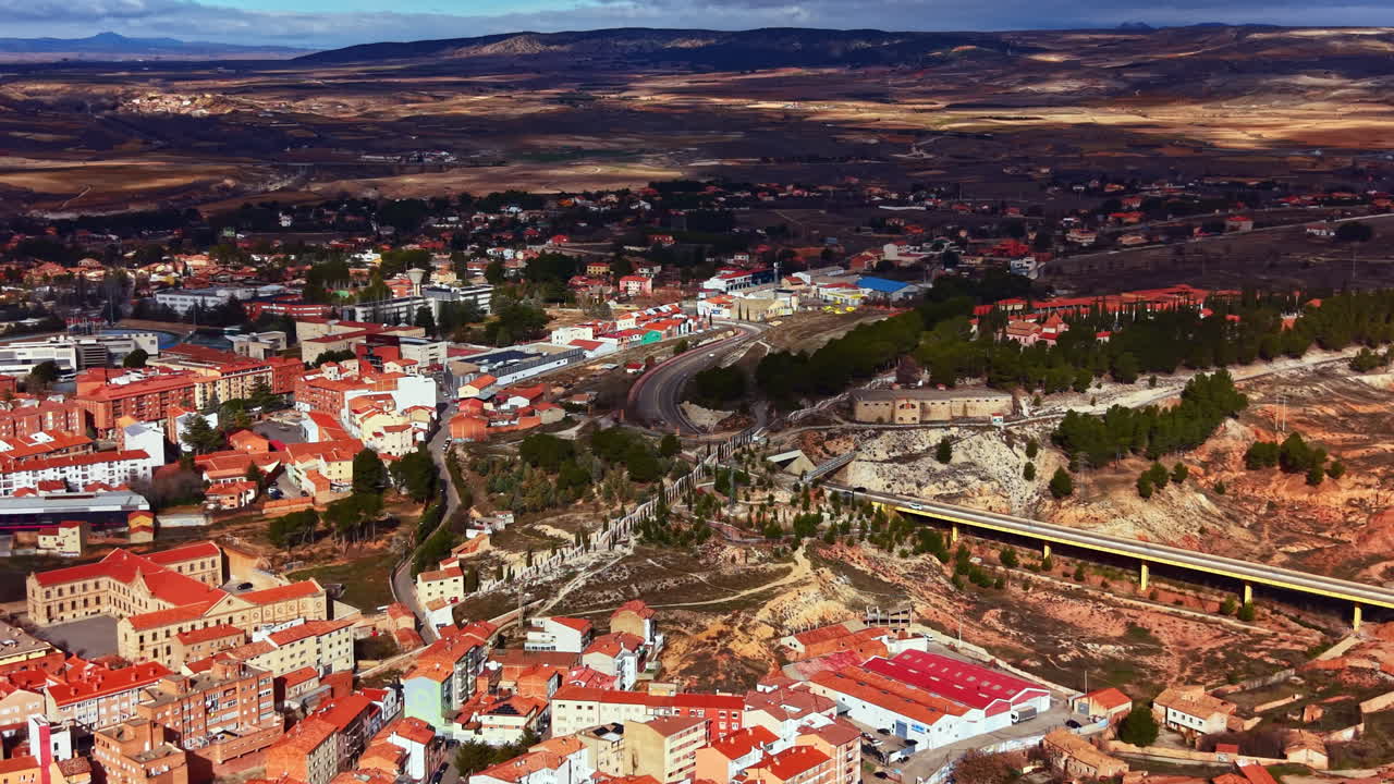 Veduta di un paese con edifici e strade in una valle circondata da colline, di giorno, in una zona rurale della Spagna.
