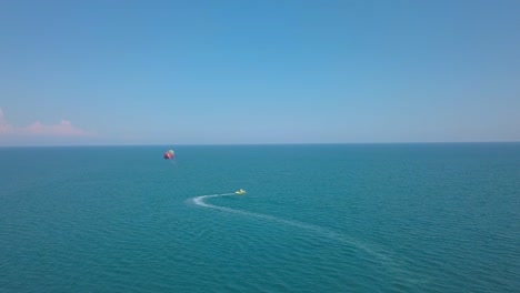 parasailing - boat with parachute cruising across the calm blue water during summer in greece