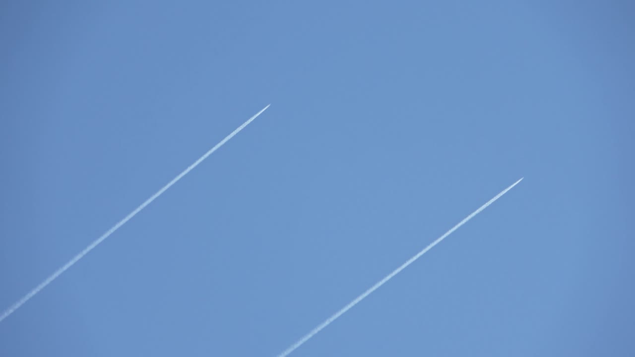 두 개의 군사 제이가 하늘을 날아다니며 은 파란 하늘에 콘트레일을 남니다.