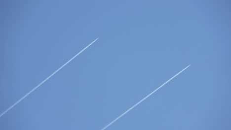 two military jeys flying high in the sky leaving contrails in the clear blue sky