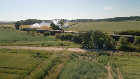 low angle aerial view of a steam engine locomotive train passing on tracks in the countryside in north england