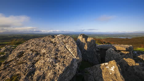 Timelapse-of-rural-nature-landscape-with-ruins-of-prehistoric-passage-tomb-stone-blocks-in-the-foreground-during-sunny-cloudy-day-viewed-from-Carrowkeel-in-county-Sligo-in-Ireland