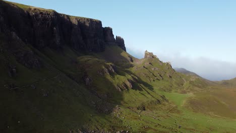 drone aéreo vuela por encima de acantilados panorámicos verdes caminata en el quiraing, isla de skye, horizonte de escocesa en verano, cámara lenta que establece la toma por encima de la formación de la montaña