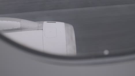view of airplane engine through window during flight on a cloudy day