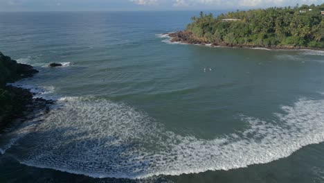 Establishing-Aerial-Drone-Shot-Over-Bay-in-Tropical-Sri-Lanka-with-Surfers-in-the-Water