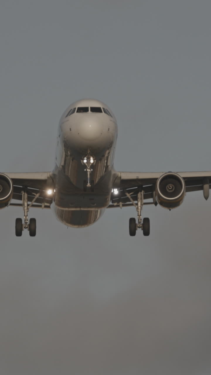 Avión volando en dirección al aeropuerto para aterrizar a cámara superlenta al atardecer en vertical