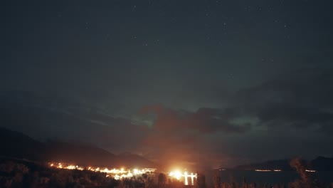 northern lights in the night sky above the brightly illuminated ort and the fjord