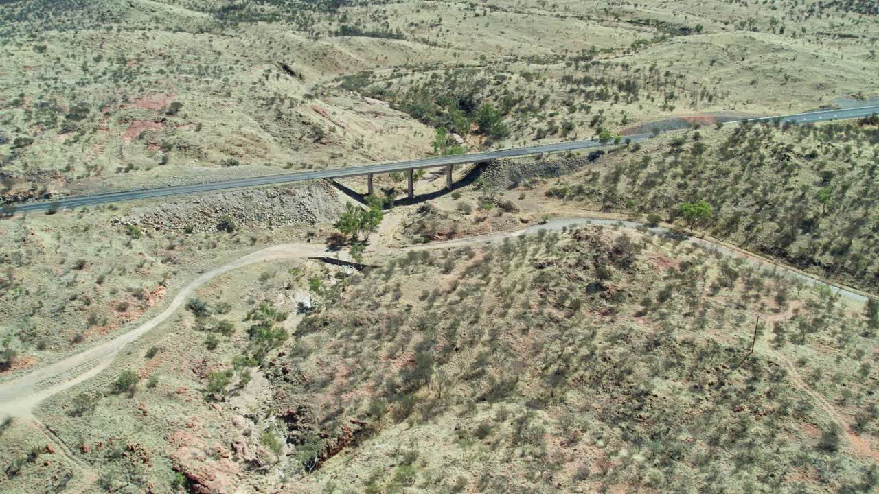Reverse drone footage of the Stuart Highway bridge over the the Charles River at Irlpme, a northern suburb of Alice Springs, Mparntwe, Northern Territory, Australia. August 2022.