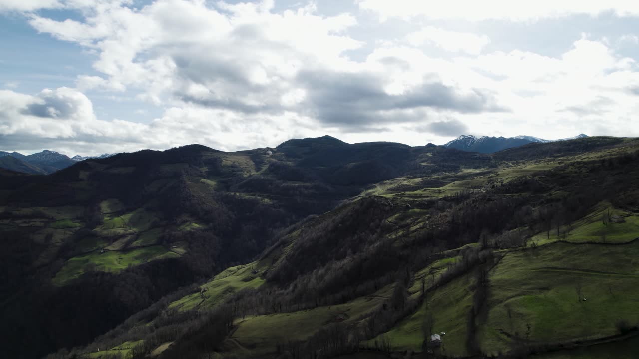 Un'ombra scura si proietta su un paesaggio montuoso e verde mentre le nuvole si addensano in alto