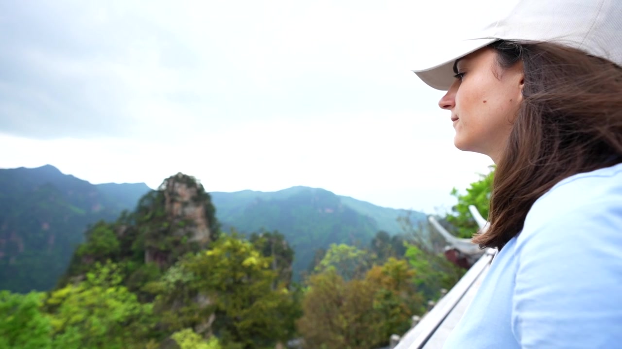 Female traveler admiring the lush landscape of Huangshi Village in Zhangjiajie National Forest Park