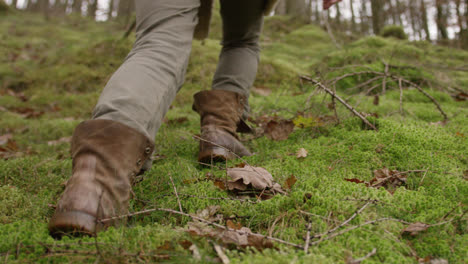 Botas-Caminando-Por-El-Suelo-Del-Bosque-Cubierto-De-Musgo