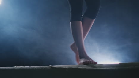 girl gymnast practicing on a balance beam in gym.