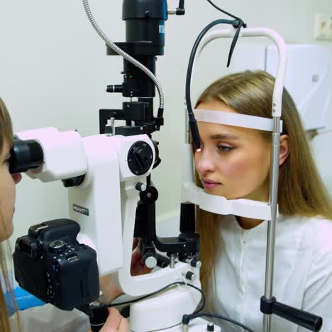 pretty young woman do eye test sitting in front of doctor. female optometrist is examining patient's eyes in medical office. ophthalmology treatment.