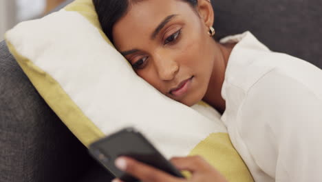 Girl-on-sofa,-smiling-and-typing-on-a-phone