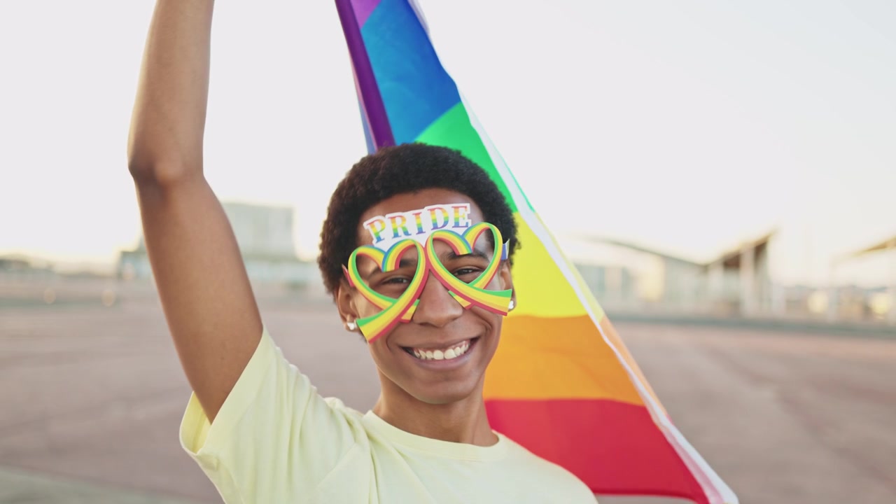 Joyful Young Person Holding Rainbow Pride Flag Outdoors