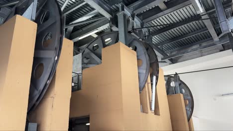 large wheels of a ski lift mechanism inside a modern building, shot from below