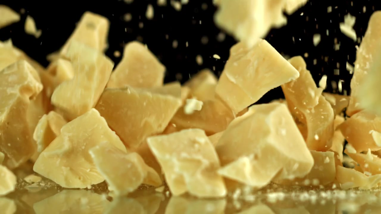 White Chocolate Pieces Falling on Black Background in Slow Motion