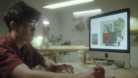 young man working on design project at computer in studio