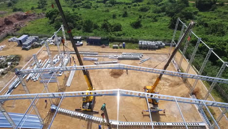 drones por encima de la cabeza, grúas de construcción levantan vigas de acero mientras los trabajadores se unen al marco