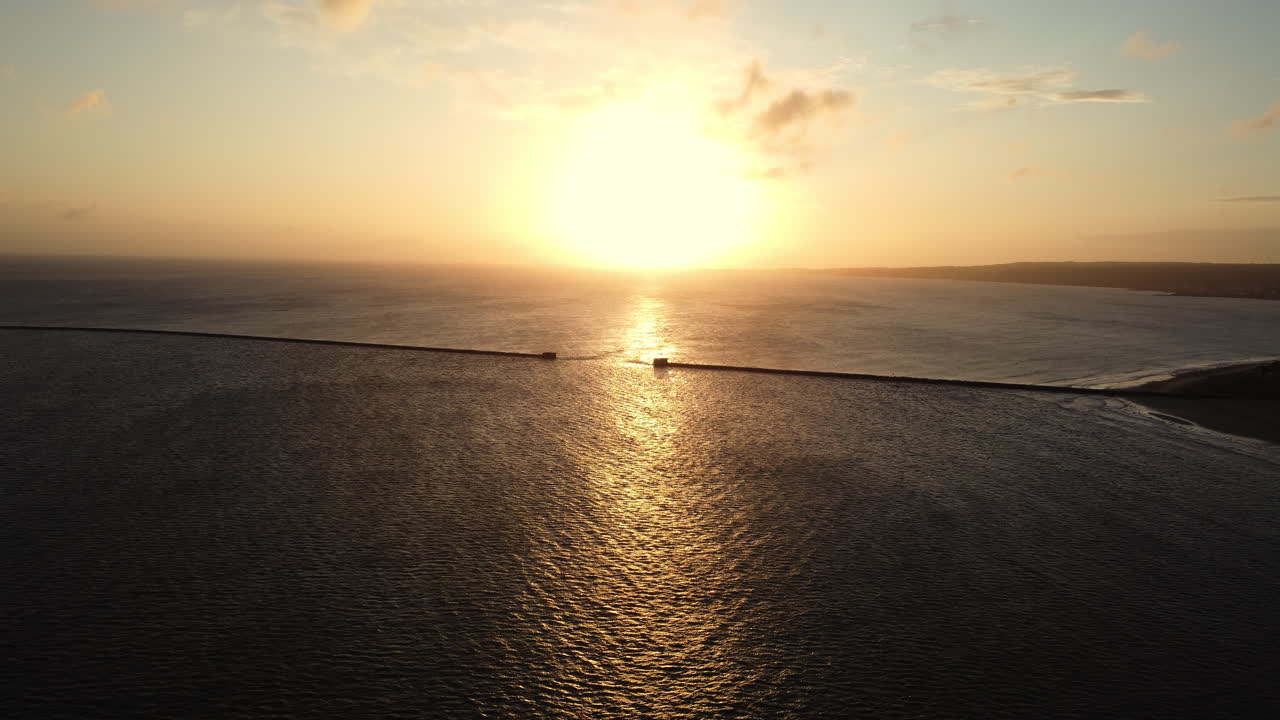Sunset over the ocean with a coastline barrier