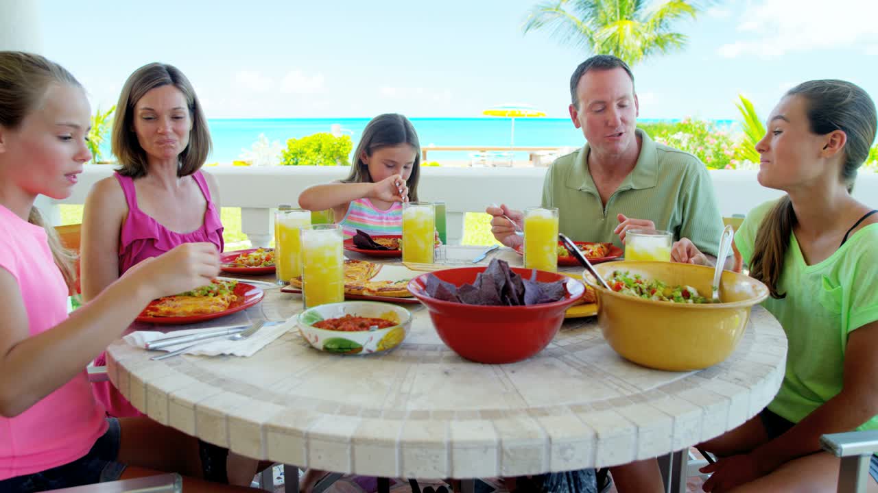 카우카스족 가족 이 해변 휴양지 에서 야외 에서 식사 하고 있다