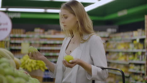 Una-Joven-Atractiva-Eligiendo-Manzana-En-El-Mercado-De-Supermercados-De-Frutas-Y-Verduras