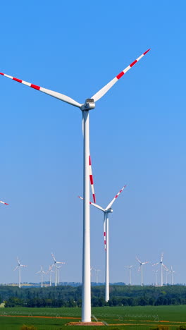 wind turbines spinning in open landscape. several wind turbines rotate under a clear blue sky in an open field, showcasing renewable energy in action