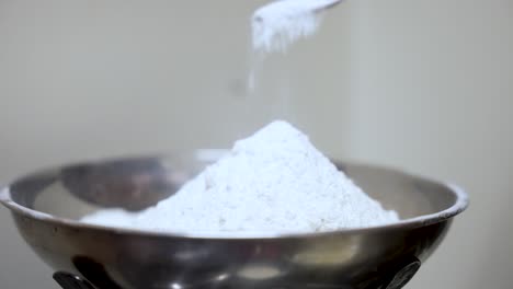 flour being measured accurately on a kitchen scale with a spoon for baking preparation.