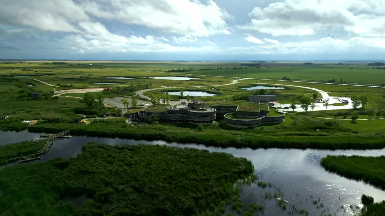 High-angle drone shows green-roof centre with roads, paths, wetlands
