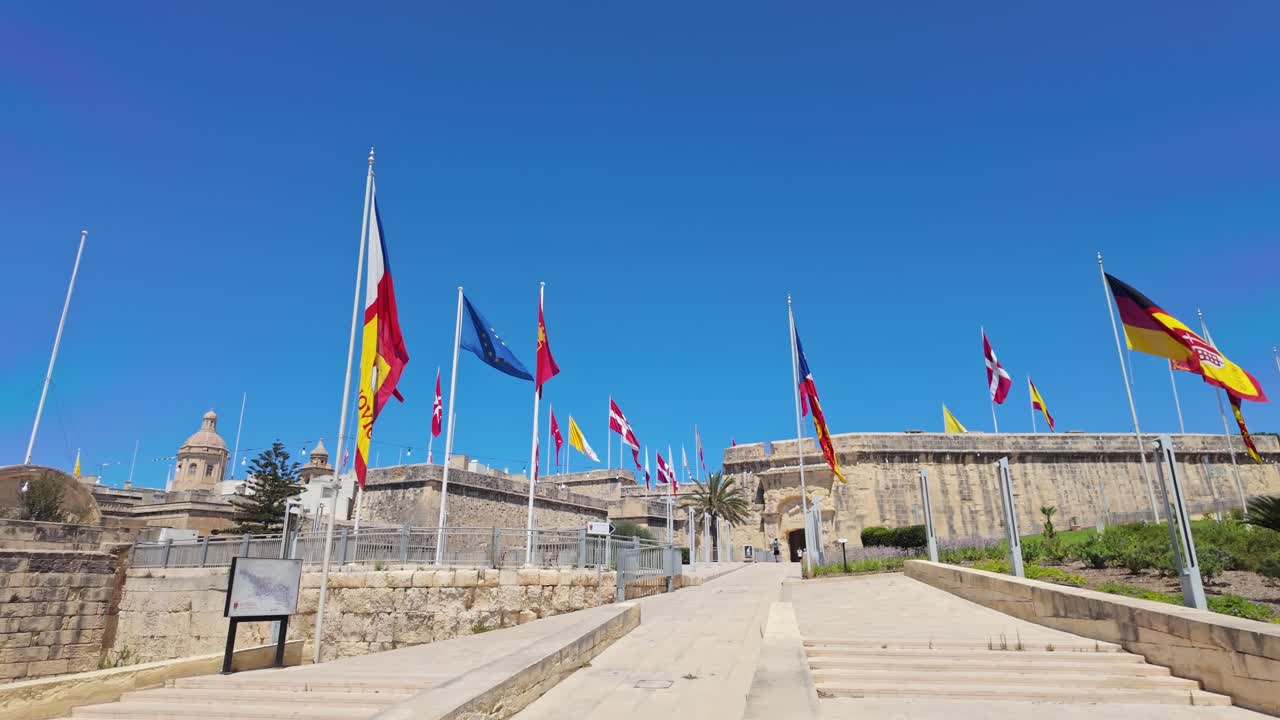 Spectacular waving festival flag decoration at the medieval entrance of Birgu on a sunny day in Malta