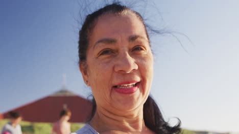 Mujer-De-Raza-Mixta-Mirando-A-La-Cámara-Y-Sonriendo-En-La-Playa-Y-El-Fondo-Del-Cielo-Azul