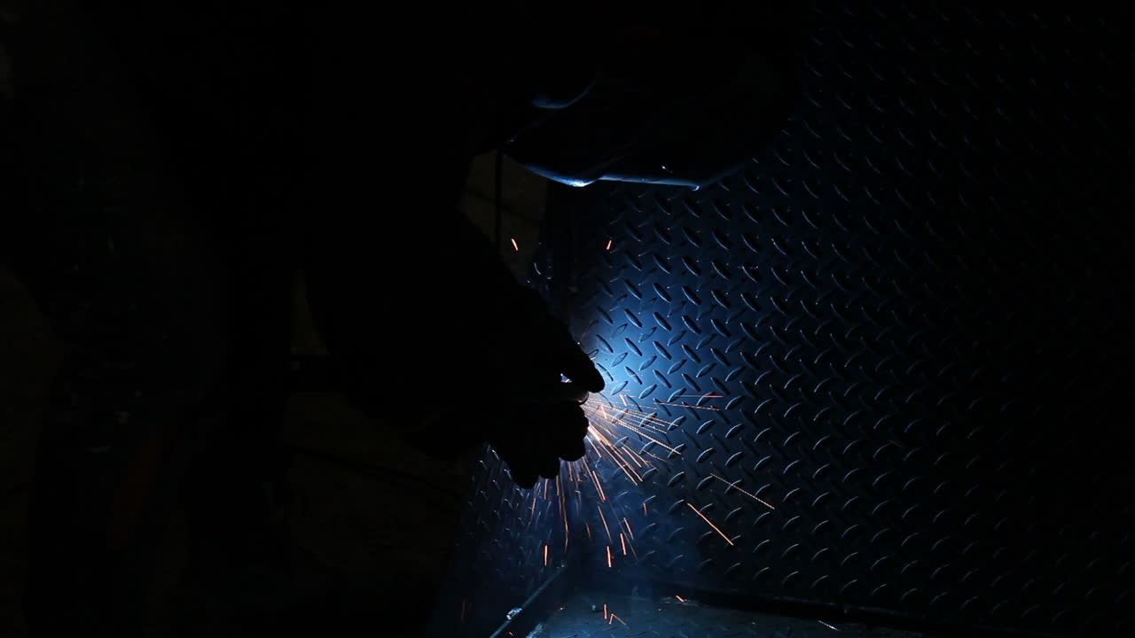 Welding arc illuminating heavy metal sheet blue as it becomes connected ready for product delivery