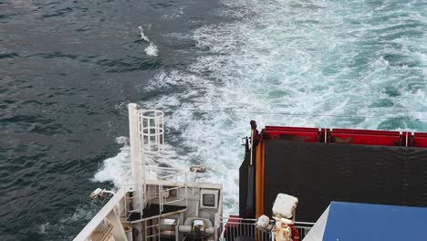 a portion of the stern of a ship with the wake behind it