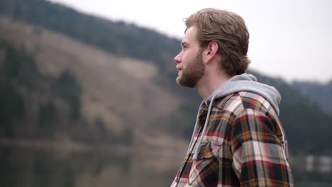 man dressed in a plaid sweater, looks thoughtfully into the distance, whereupon a hearty grin came out of him