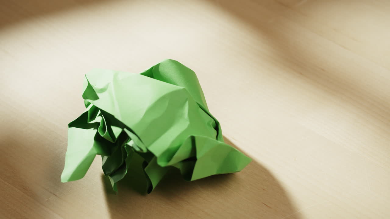 Hands folding green paper on table
