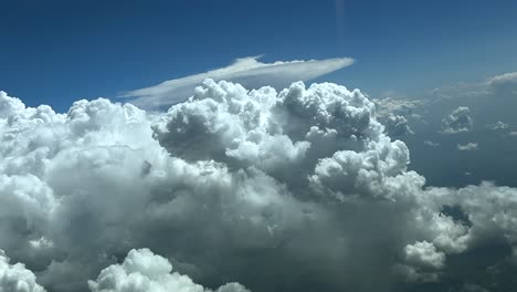 an immersive pilot view from a jet cockpit flying at cruise level with massive and threatening cumulonimbus storm clouds ahead, doind a right turn to avoid, under a blue sky. ultra-realistic 4k.