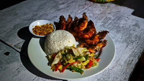 profile view of udang bakar dish served on white plate in bali, indonesia.