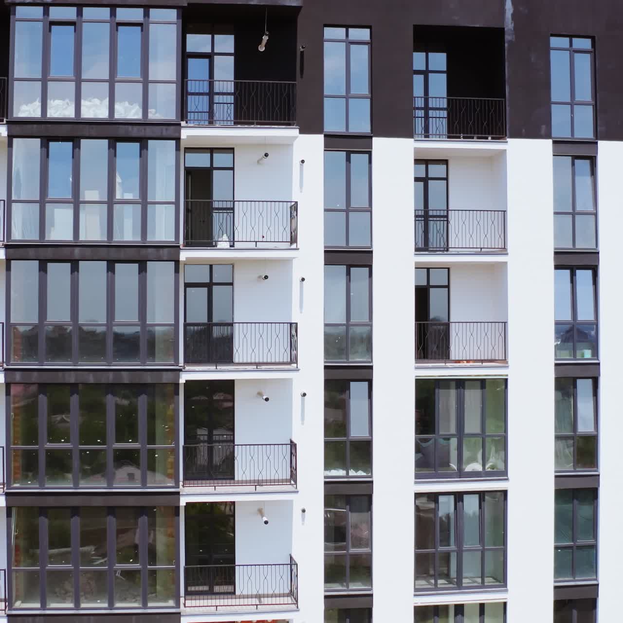 Black and white block of flats. Front view of a modern multi-storey building with glazed balconies in the city. Beautiful new housing apartments