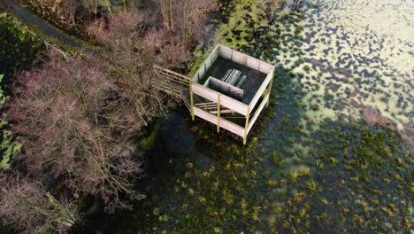 Wooden-Birdwatching-Tower-on-Wetland-in-Sweden---Drone-Shot,-Ascending-Pullback